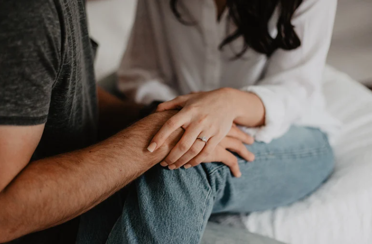 Elderly woman shaking hands with man sitting on couch